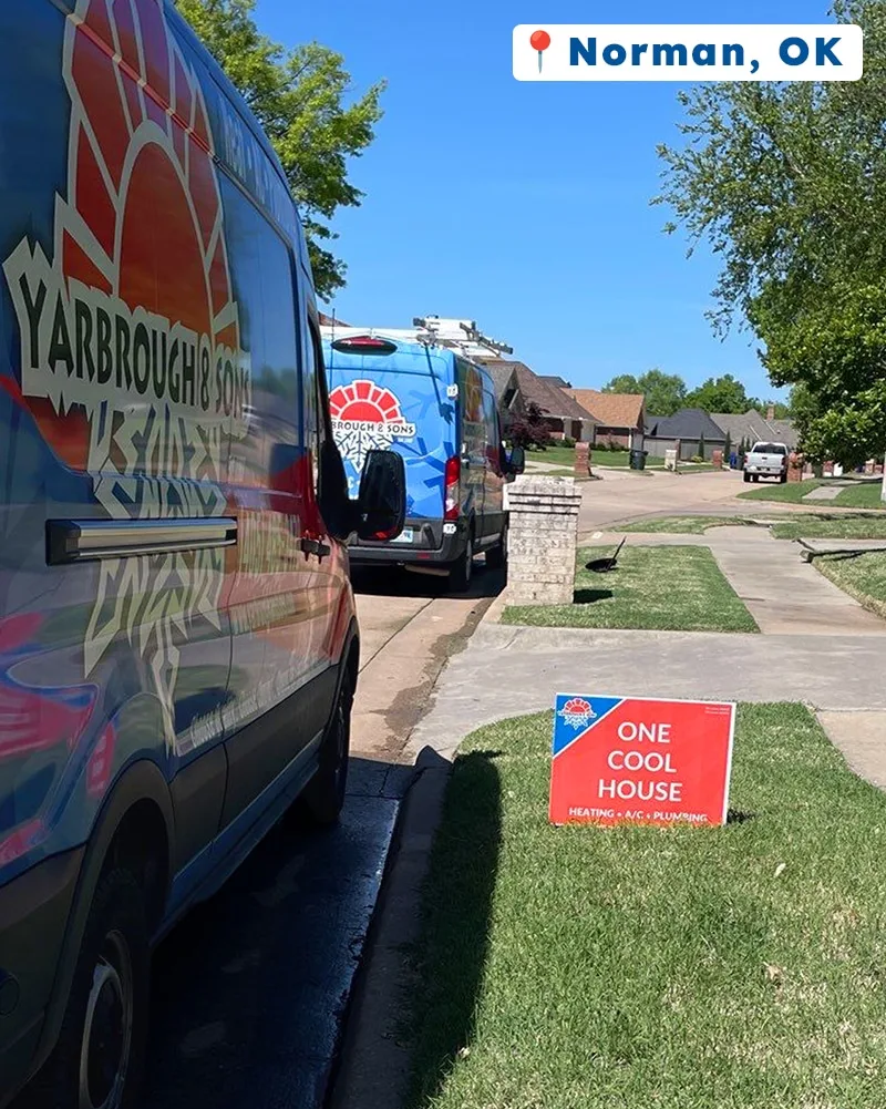 Two Yarbrough & Sons service vans parked at a Norman, OK home, with a “One Cool House” yard sign displayed on the lawn after completing HVAC maintenance and plumbing upgrades.