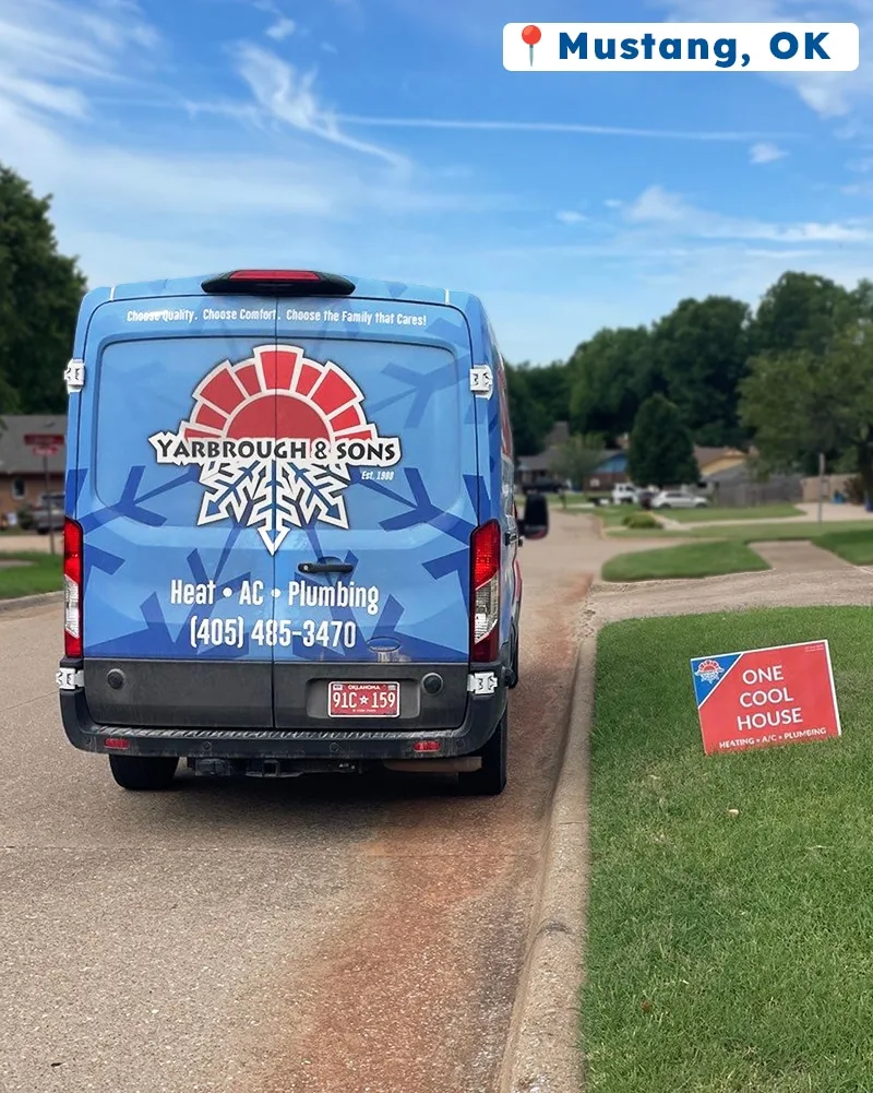 Rear view of a Yarbrough & Sons service van parked on a residential street in Mustang, OK, with a “One Cool House” yard sign on the grass.