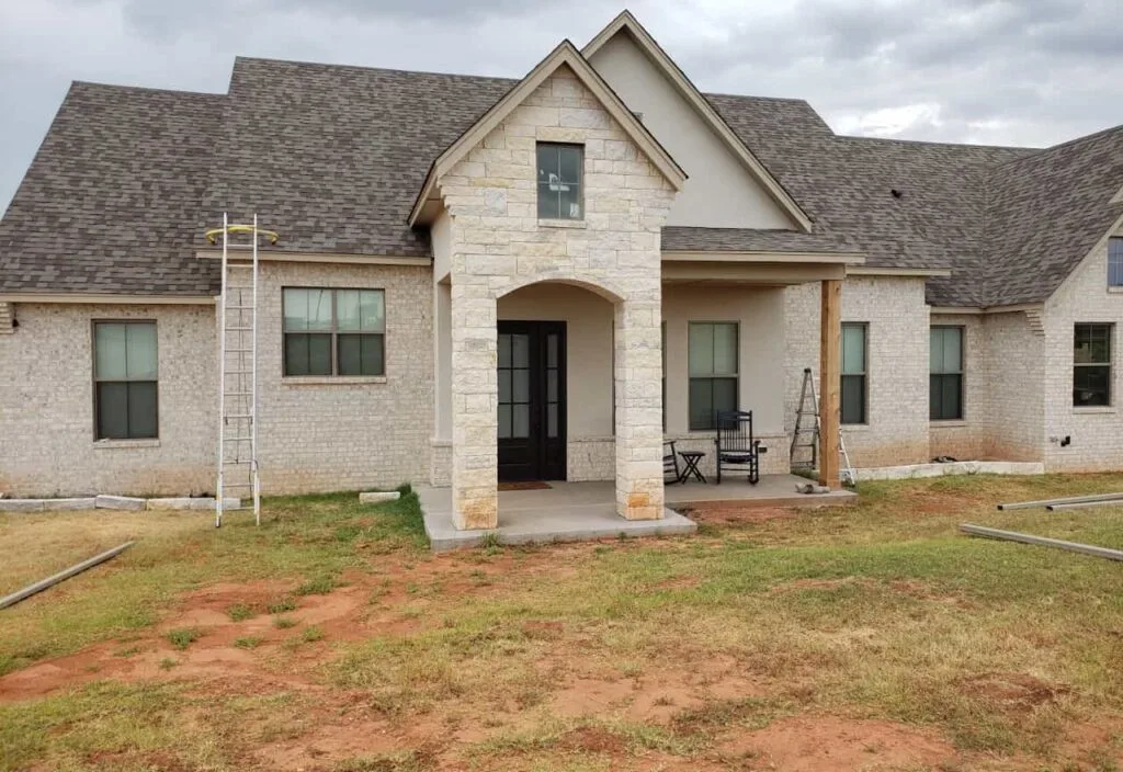 Front view of a newly built house with a porch and outdoor chairs.
