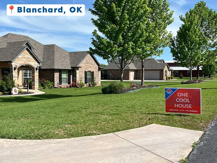 A well-maintained brick home in Blanchard, OK, with a bright red “One Cool House” yard sign on the green front lawn, signaling recent HVAC service by Yarbrough & Sons.