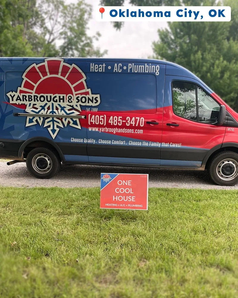 Yarbrough & Sons service van parked on a gravel driveway in front of a grassy yard in Oklahoma City, OK. A bright red yard sign reading “ONE COOL HOUSE – HEATING • A/C • PLUMBING” is displayed prominently in the foreground.