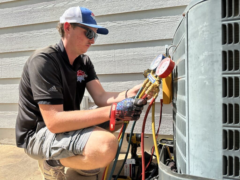 Yarbrough & Sons Heating, Cooling & Plumbing service technician Canon Owens checks pressure gauges on a 2006 AC unit at a customer's house.