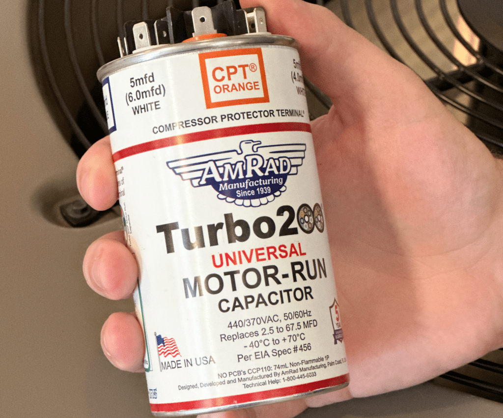 A Turbo 200 AC capacitor held over an AC condenser.